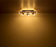 Moderne Deckenleuchte mit drei Strahlern, von unten betrachtet, die warmes Licht an die Decke und den Raum abgibt.
