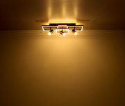 Moderne Deckenleuchte mit drei Strahlern, von unten betrachtet, die warmes Licht an die Decke und den Raum abgibt.