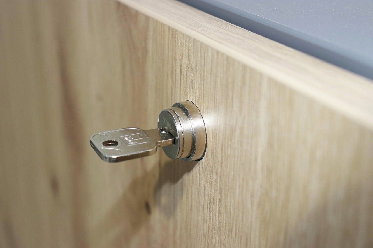 Nahaufnahme eines Schlüssels in einem Schloss an einem Wandschreibtisch aus Holz, seitliche Perspektive.