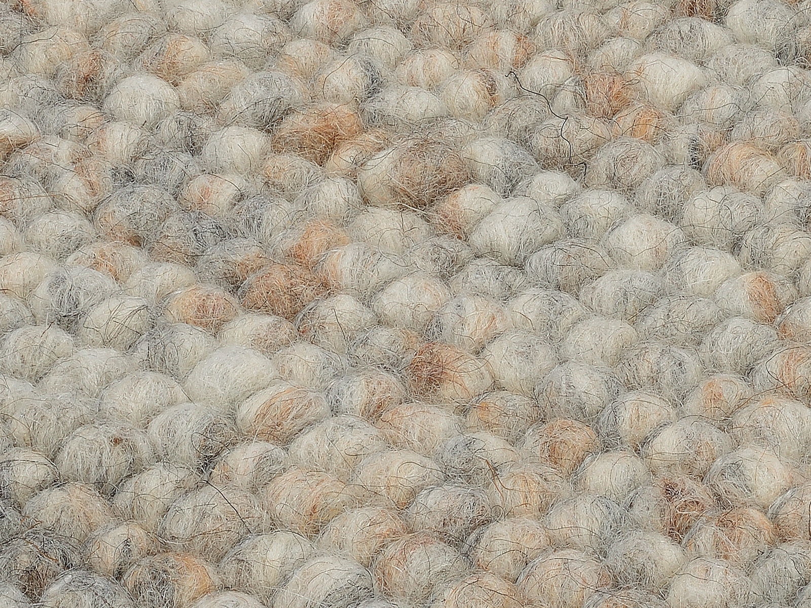 Nahaufnahme eines handgewebten Teppichs mit einer texturierten Oberfläche aus dicken, gefilzten Wollkugeln in natürlichen Beige- und Grautönen.