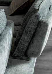 Nahaufnahme eines grauen Longchairs mit weicher Polsterung, seitliche Perspektive