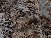 Nahaufnahme eines Designer-Teppichs mit braunen und grauen Mustern, perspektivisch von der Seite aufgenommen.