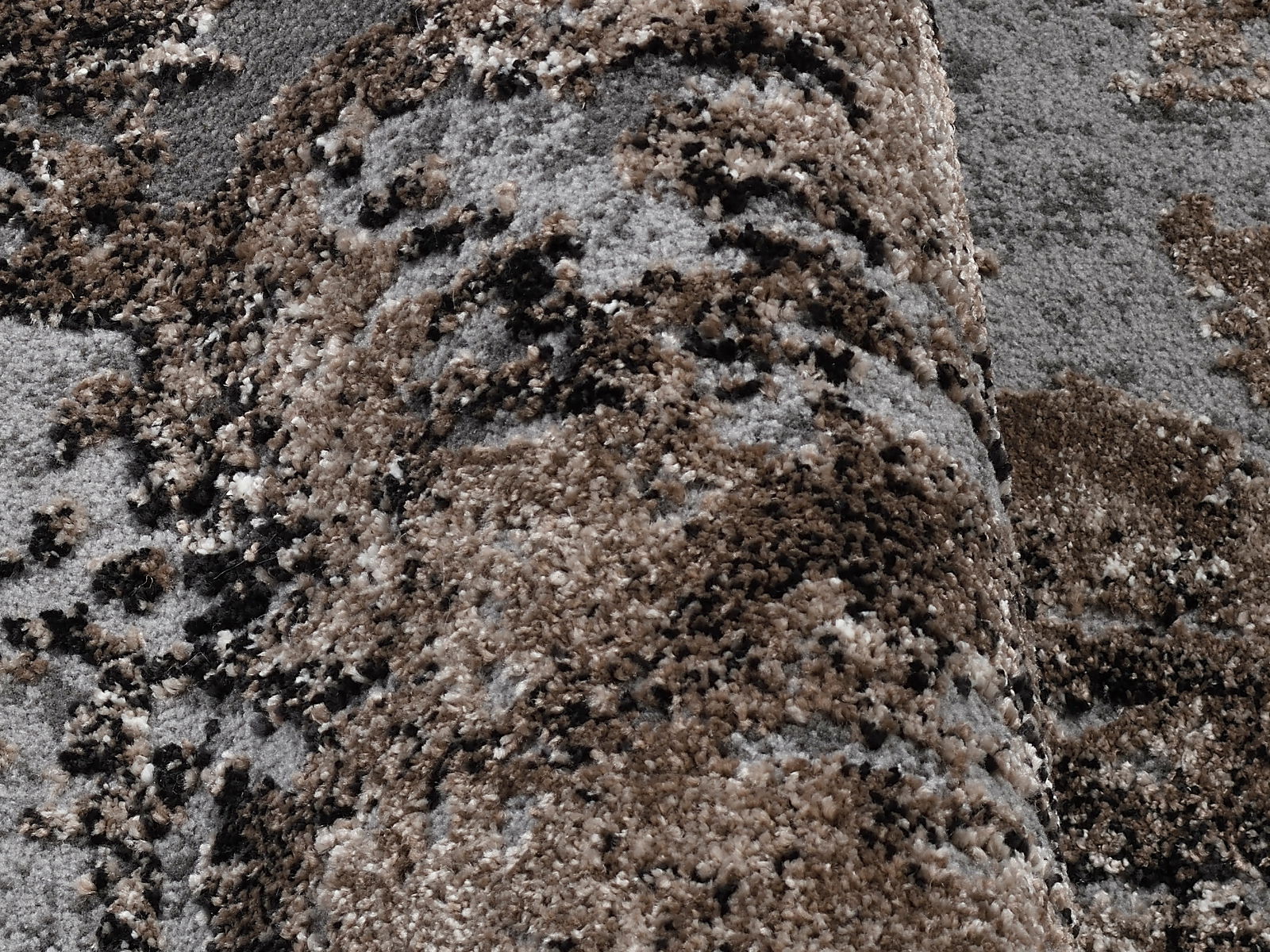 Nahaufnahme eines Designer-Teppichs mit braunen und grauen Mustern, perspektivisch von der Seite aufgenommen.