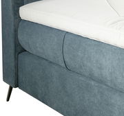 Nahaufnahme eines Boxspringbetts 180x200 mit grauem Stoffbezug und weißer Matratze, seitliche Perspektive