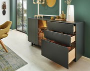 Modernes Sideboard mit offenen Schubladen, seitliche Perspektive, dekoriert mit Geschirr und einer Vase, vor einer grünen Wand.