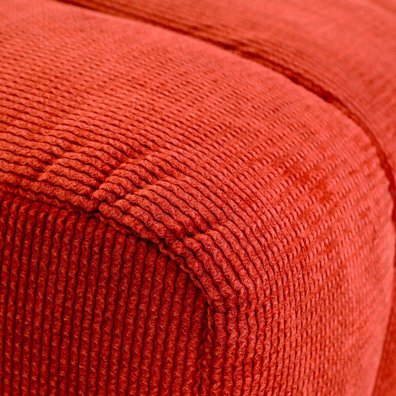 Novel Hocker LAILA Nahaufnahme eines roten, strukturierten Hockers aus Stoff, perspektivisch von der Seite aufgenommen.