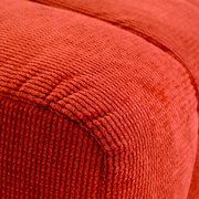 Nahaufnahme eines roten, strukturierten Hockers aus Stoff, perspektivisch von der Seite aufgenommen.