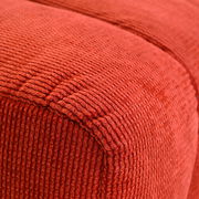 Nahaufnahme eines roten, strukturierten Hockers aus Stoff, perspektivisch von der Seite aufgenommen.