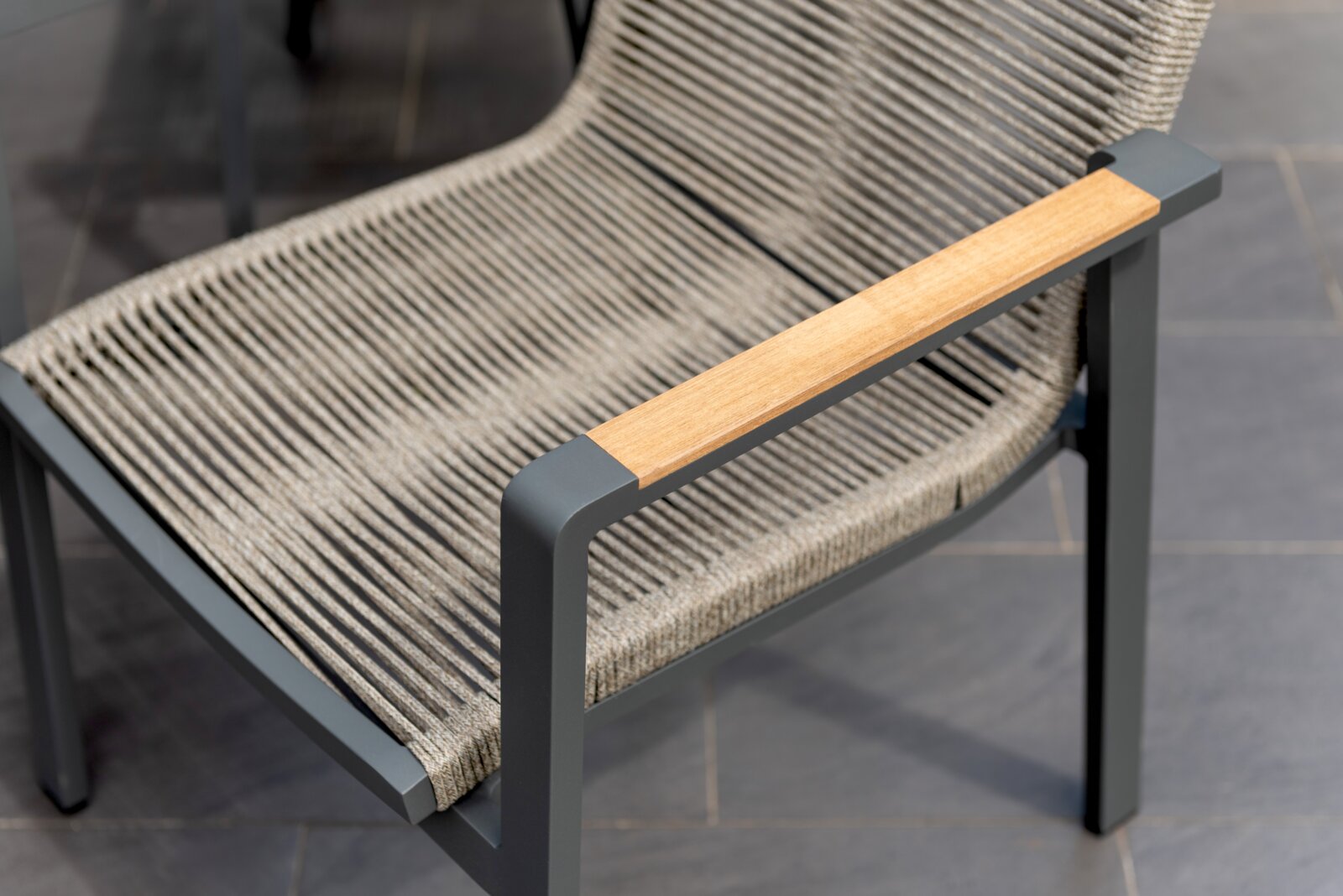 Moderne stapelbare stoel met grijs metalen frame en gevlochten zitting, zijaanzicht