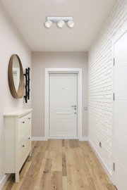 Deckenansicht eines modernen LED Strahlers mit drei verstellbaren Leuchten in einem hellen Flur.