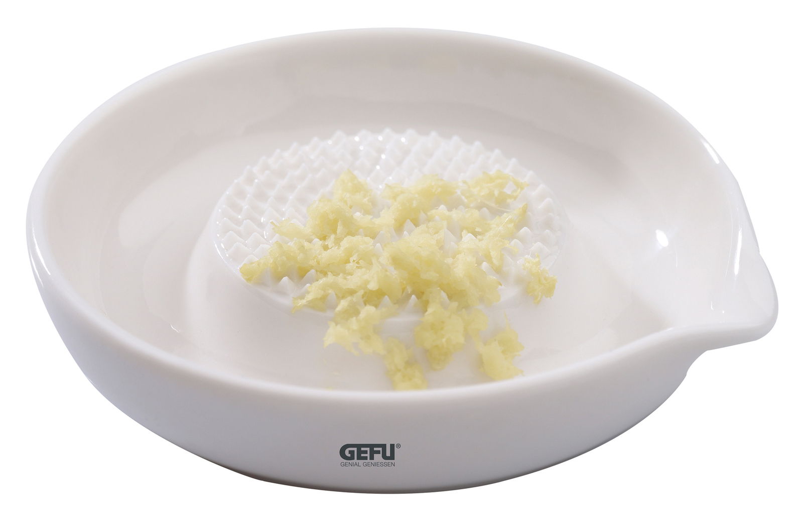 Runde Ingwerreibe aus weißem Material mit geriebener Ingwer auf der Oberfläche, seitliche Perspektive.