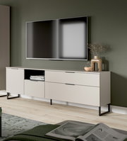 Modernes, hellbeiges TV-Lowboard mit schwarzen Metallfüßen und Schubladen unter einem wandmontierten Flachbildfernseher, dekoriert mit Vase und Glasobjekt; Perspektive: leicht schräg von vorn aus Augenhöhe.