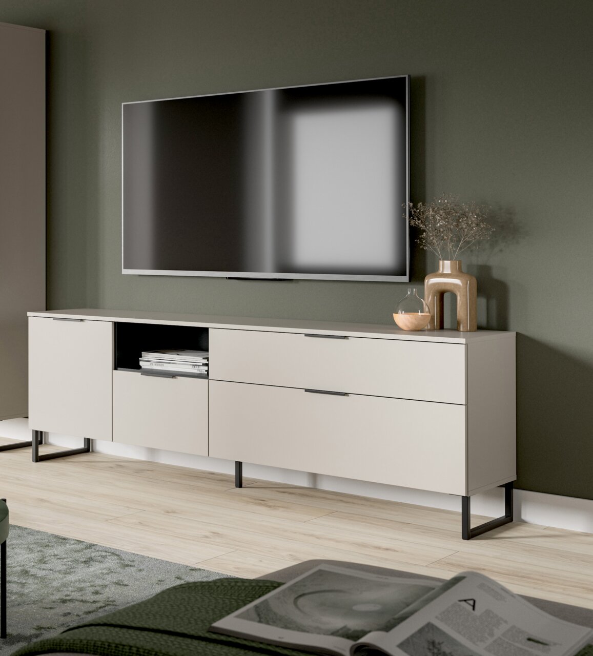 MID.YOU TV Lowboard NOIDA Modernes, hellbeiges TV-Lowboard mit schwarzen Metallfüßen und Schubladen unter einem wandmontierten Flachbildfernseher, dekoriert mit Vase und Glasobjekt; Perspektive: leicht schräg von vorn aus Augenhöhe.