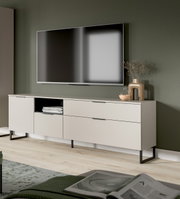 Modernes, hellbeiges TV-Lowboard mit schwarzen Metallfüßen und Schubladen unter einem wandmontierten Flachbildfernseher, dekoriert mit Vase und Glasobjekt; Perspektive: leicht schräg von vorn aus Augenhöhe.