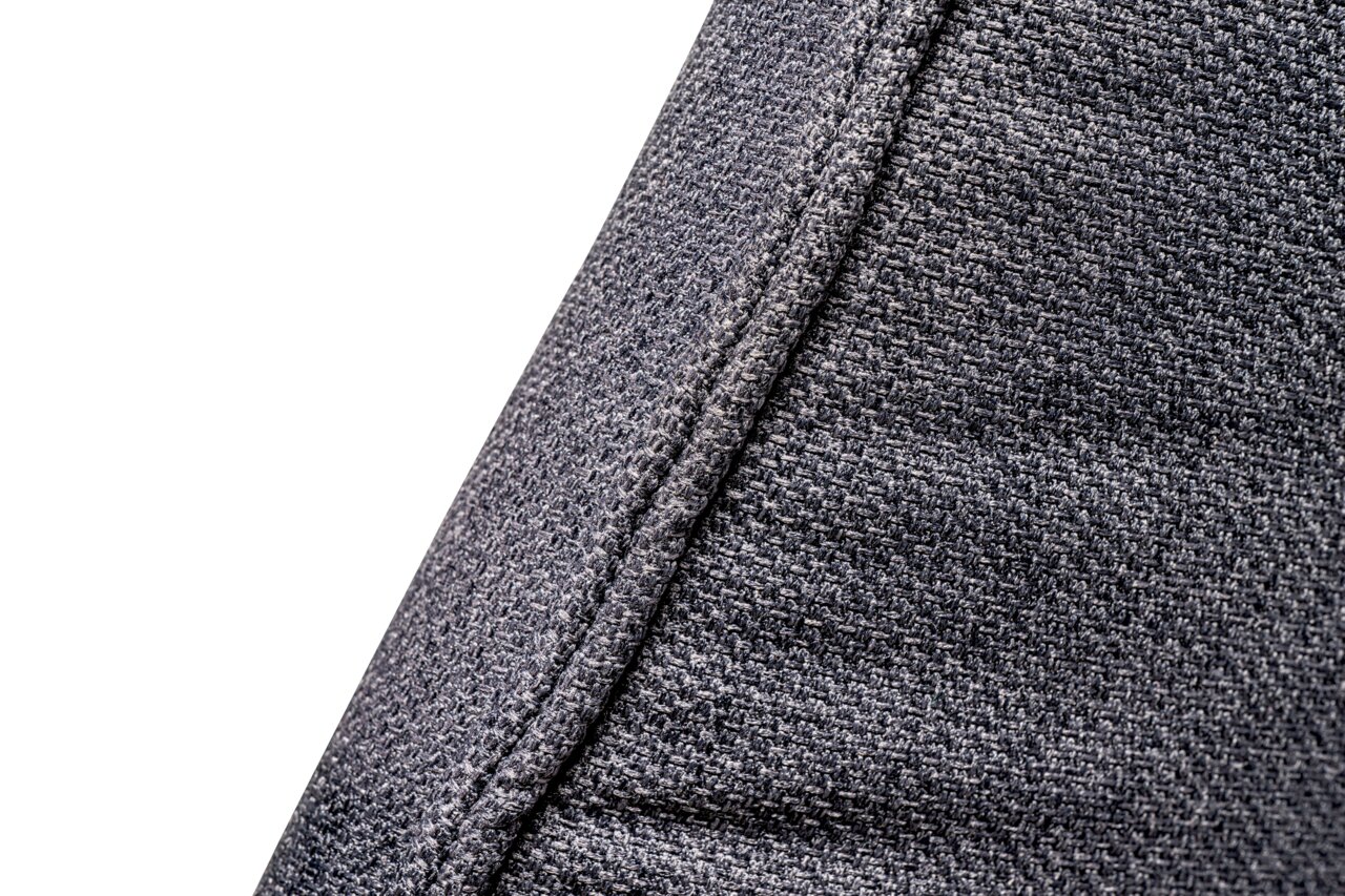 Nahaufnahme des grauen Stoffbezugs eines XL-Drehstuhls, seitliche Perspektive