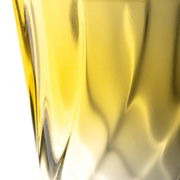 Nahaufnahme eines gelben Trinkglases mit gedrehtem Design, seitliche Perspektive