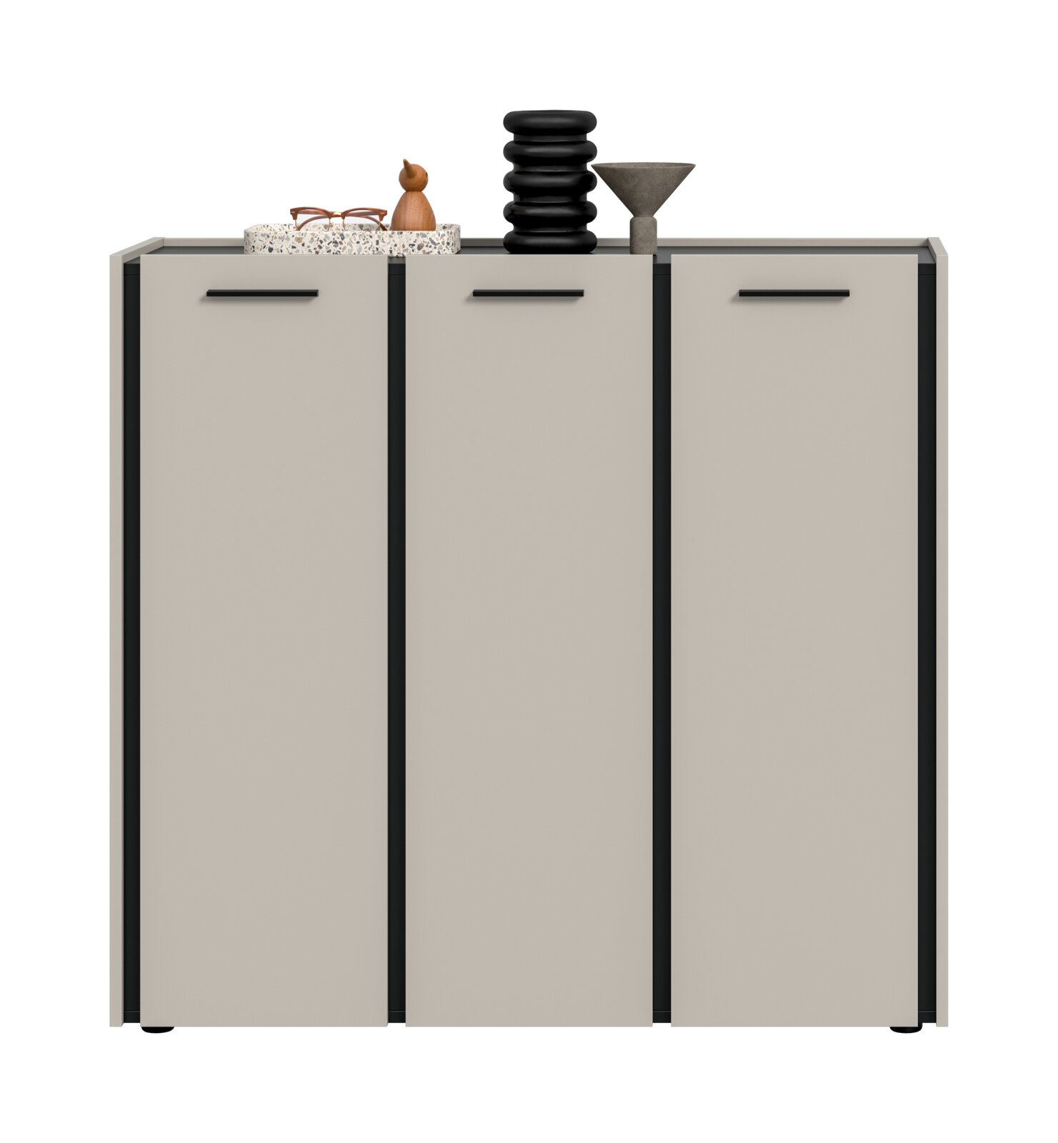 Modernes Sideboard/Kommode in Hellgrau mit drei Türen und schwarzen Griffleisten, freigestellt auf weißem Hintergrund; Frontansicht von leicht schräg oben, mit Deko (Brille, Holzfigur, schwarze Vase, graue Schale) auf der Oberplatte.
