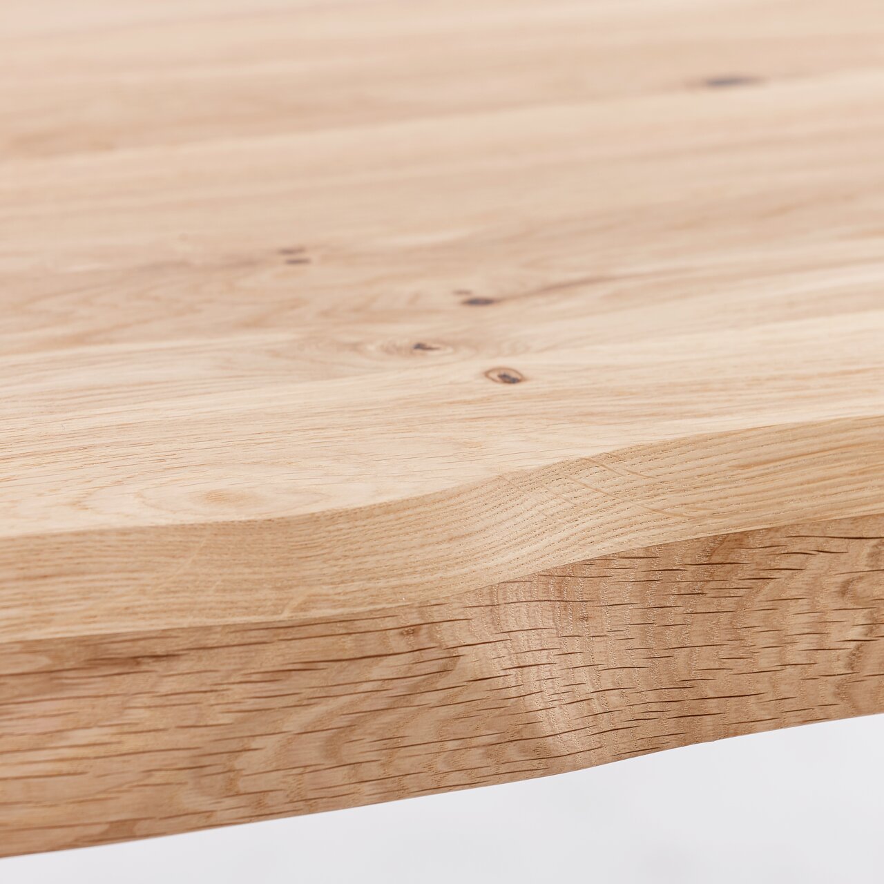 Nahaufnahme einer Tischplatte aus hellem Holz mit natürlicher Maserung, seitliche Perspektive