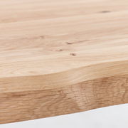 Nahaufnahme einer Tischplatte aus hellem Holz mit natürlicher Maserung, seitliche Perspektive
