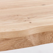 Nahaufnahme einer Tischplatte aus hellem Holz mit natürlicher Maserung, seitliche Perspektive