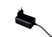 Schwarzes Netzteil mit EU-Stecker und fest angeschlossenem Kabel, freigestellt auf weißem Hintergrund, in schräger Seitenansicht von oben