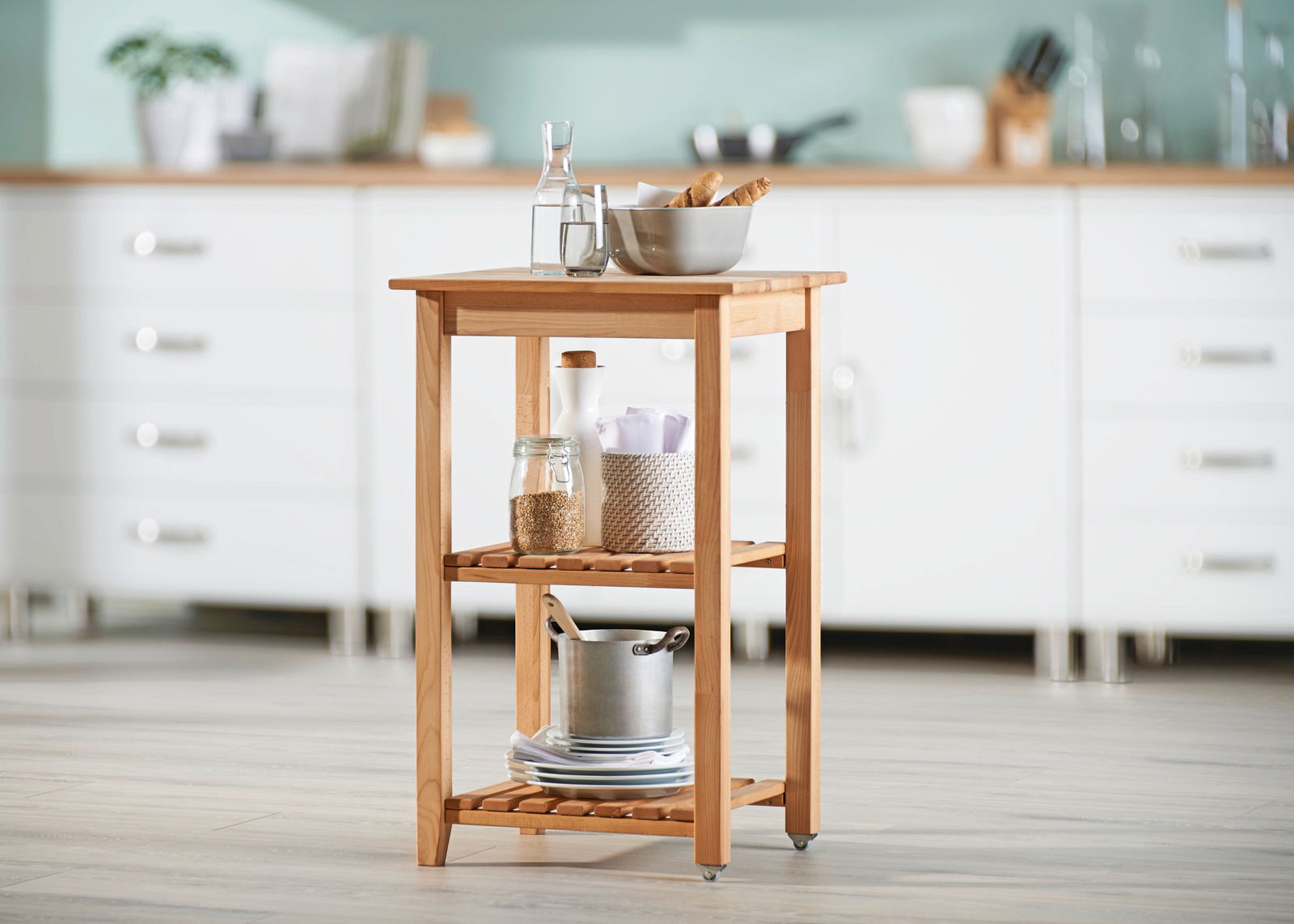Holz-Servierwagen mit zwei Regalböden, gefüllt mit Küchenutensilien, in einer modernen Küche, seitliche Perspektive