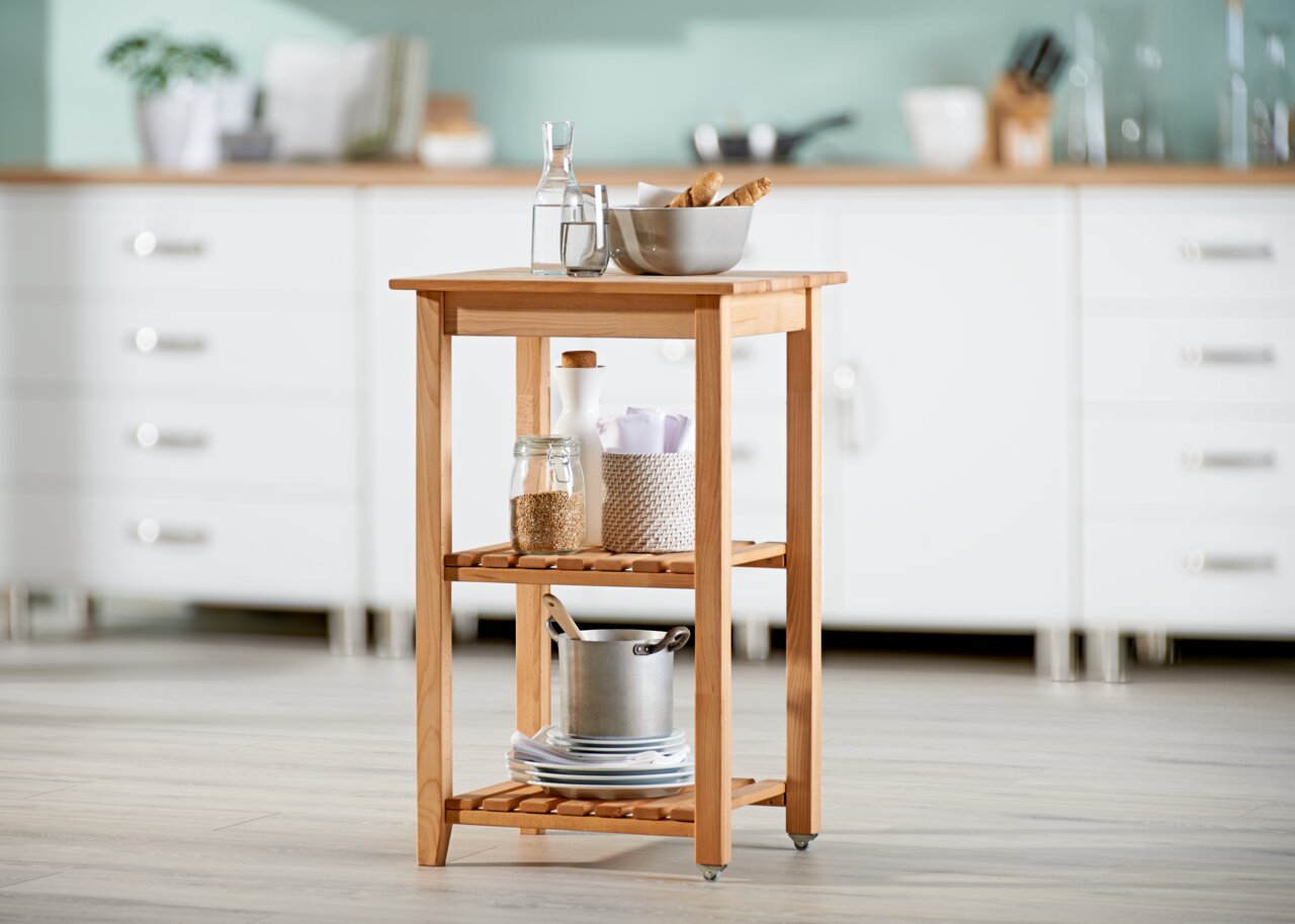 Holz-Servierwagen mit zwei Regalböden, gefüllt mit Küchenutensilien, in einer modernen Küche, seitliche Perspektive