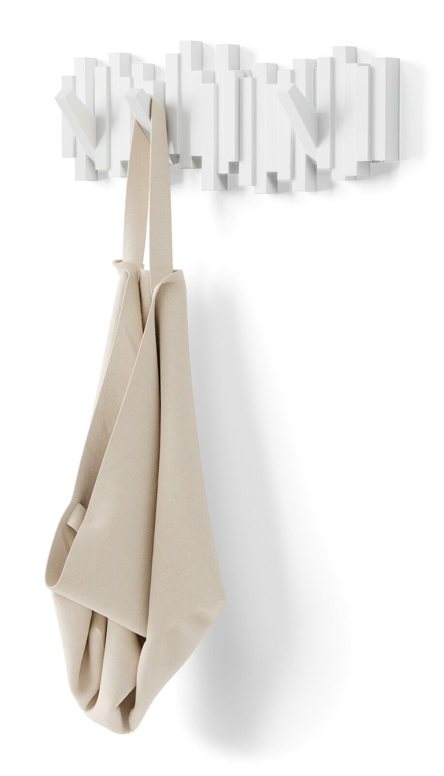 Moderne weiße Wandgarderobe mit geometrischem Design, frontal betrachtet, mit einem beigen Stoffbeutel daran hängend.