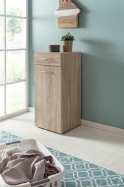Wäschekommode aus Holz in einer Ecke eines hellen Raumes, mit einer Pflanze und einer kleinen Box darauf, seitliche Perspektive