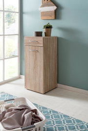 Wäschekommode aus Holz in einer Ecke eines hellen Raumes, mit einer Pflanze und einer kleinen Box darauf, seitliche Perspektive
