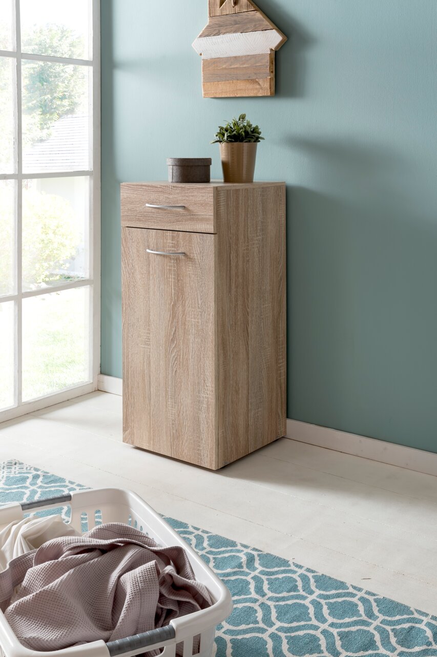 Wäschekommode aus Holz in einer Ecke eines hellen Raumes, mit einer Pflanze und einer kleinen Box darauf, seitliche Perspektive