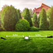 Erweiterungsset aus Edelstahl mit einer runden Leuchte auf einer grünen Rasenfläche, verbunden durch Kabel mit 0,5 m Abstand. Perspektive: seitliche Ansicht.