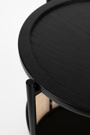 Nahaufnahme eines schwarzen Beistelltisches mit runder Tischplatte und vertikalen Stützen, seitliche Perspektive.