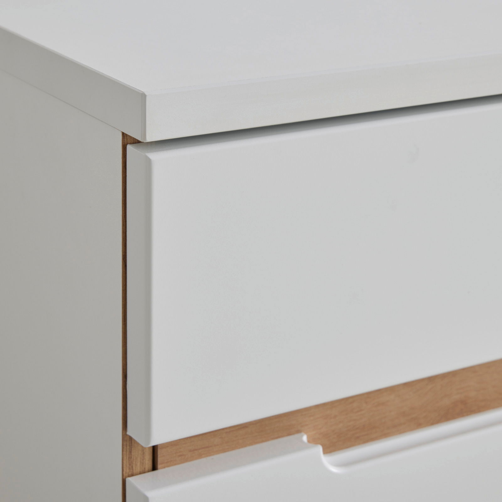 Nahaufnahme einer weißen Kommode mit Holzdetails, seitliche Perspektive