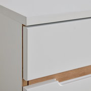 Nahaufnahme einer weißen Kommode mit Holzdetails, seitliche Perspektive