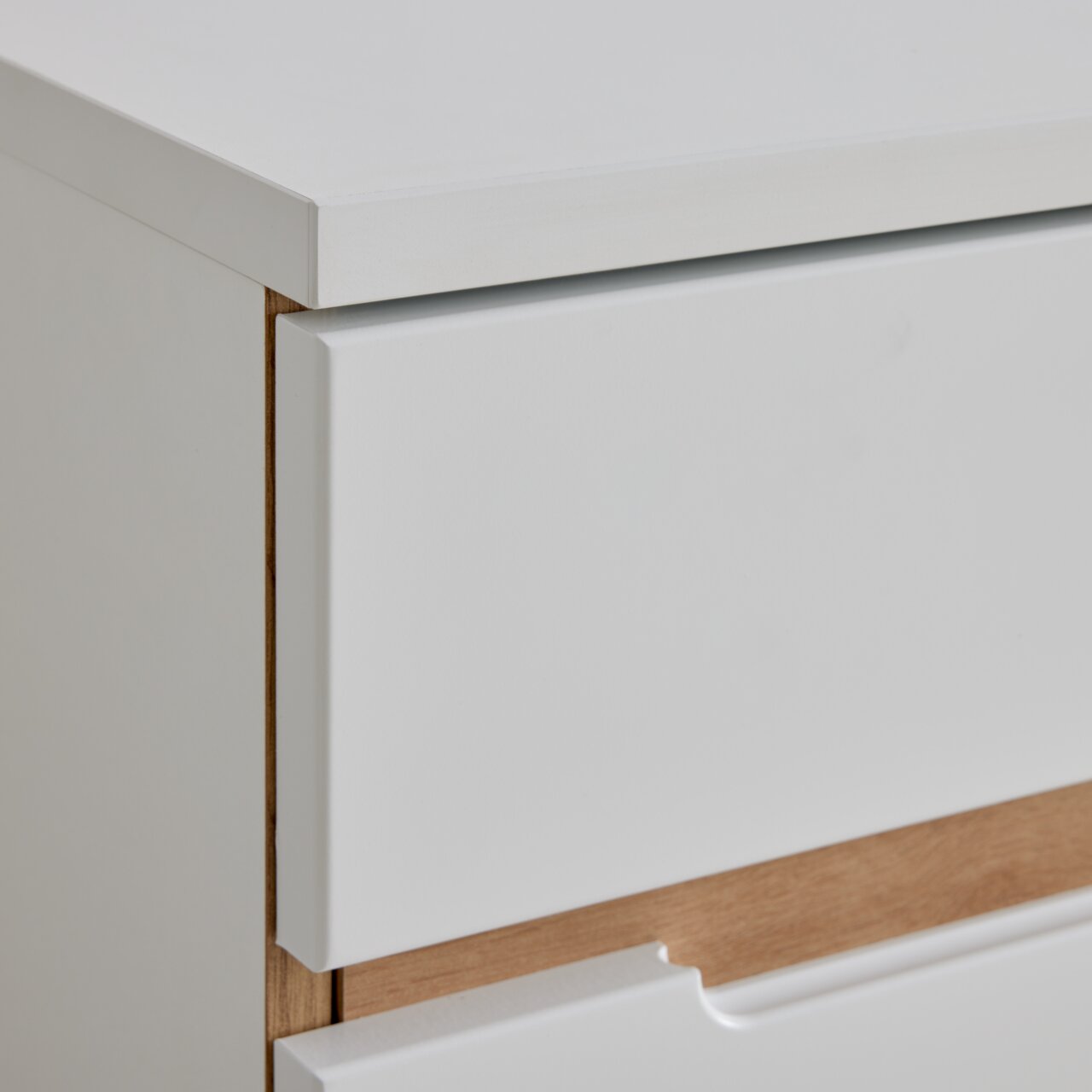 Nahaufnahme einer weißen Kommode mit Holzdetails, seitliche Perspektive