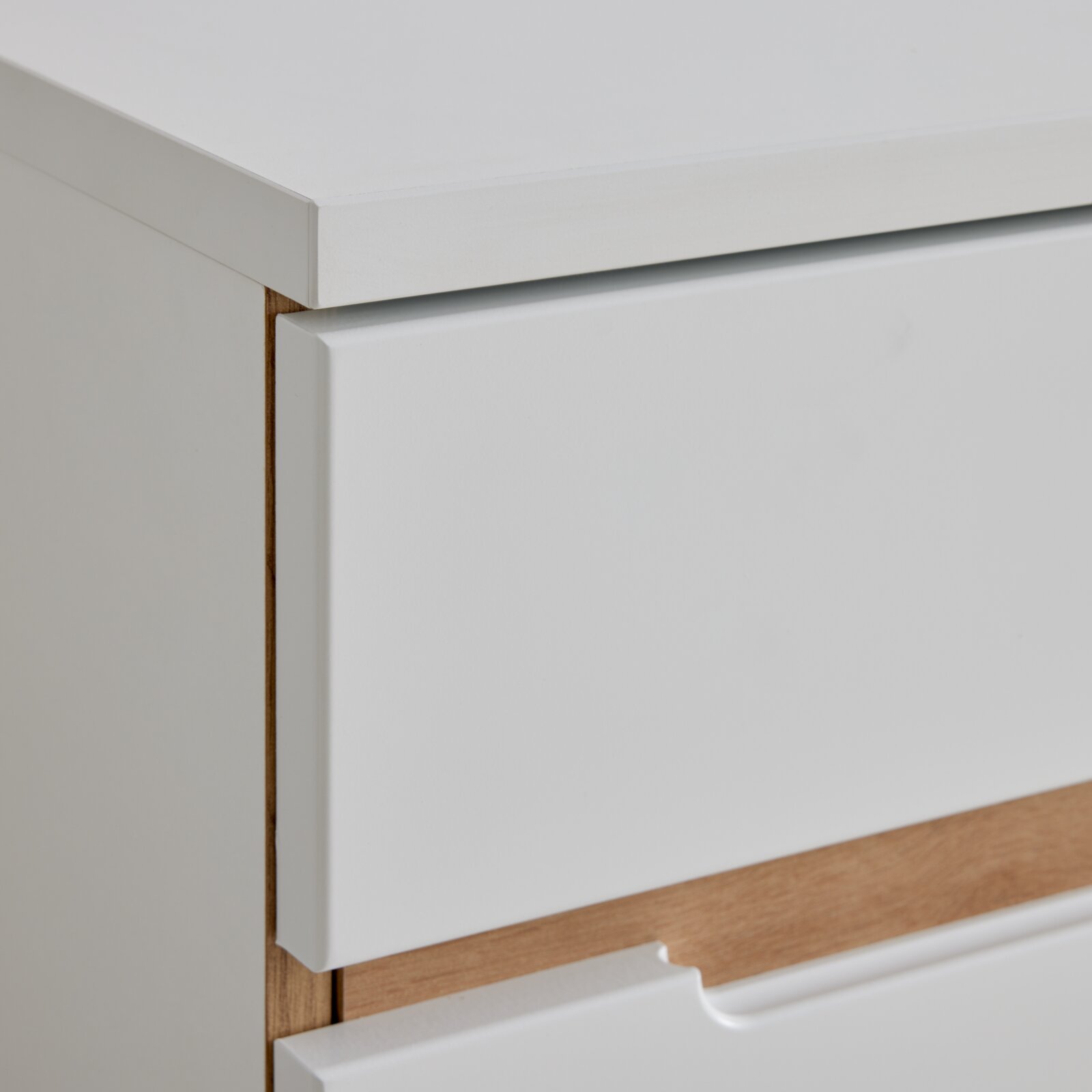 Close-up van een witte ladekast met houten details, zijaanzicht