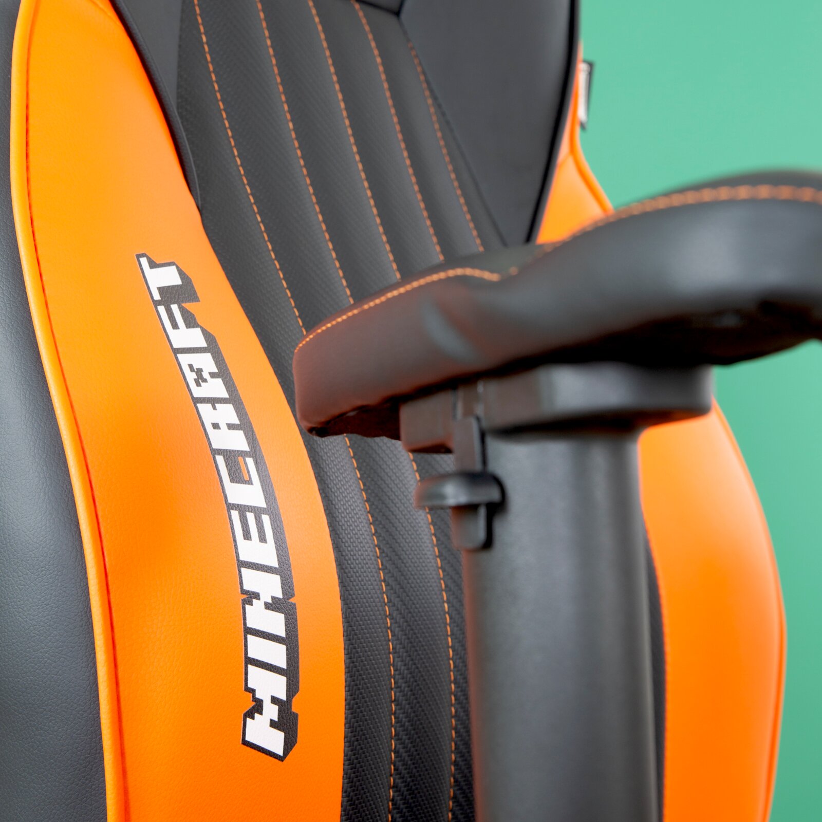 Nahaufnahme eines Gaming-Stuhls mit orangefarbenen und schwarzen Details, Minecraft-Logo auf der Rückenlehne, seitliche Perspektive