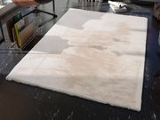 Fellteppich in einem modernen Raum, von oben betrachtet, mit einem weichen, cremefarbenen Design auf dunklem Boden.