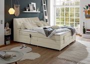 Boxspringbett in einem modernen Schlafzimmer mit großen Fenstern, seitliche Perspektive