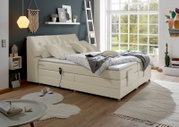 Boxspringbett in einem modernen Schlafzimmer mit großen Fenstern, seitliche Perspektive