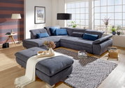 Gemütliche Polsterrundecke in modernem Wohnzimmer mit Hocker, aus der Perspektive von vorne links fotografiert.