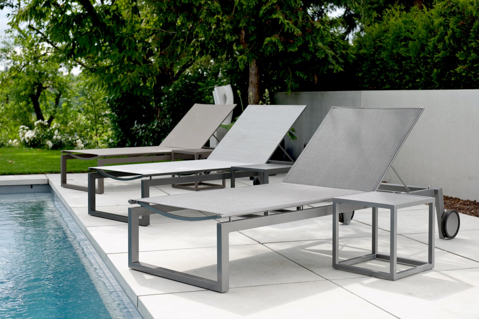 Moderne Rollenliege aus Metall in einer Gartenumgebung, seitliche Perspektive am Pool