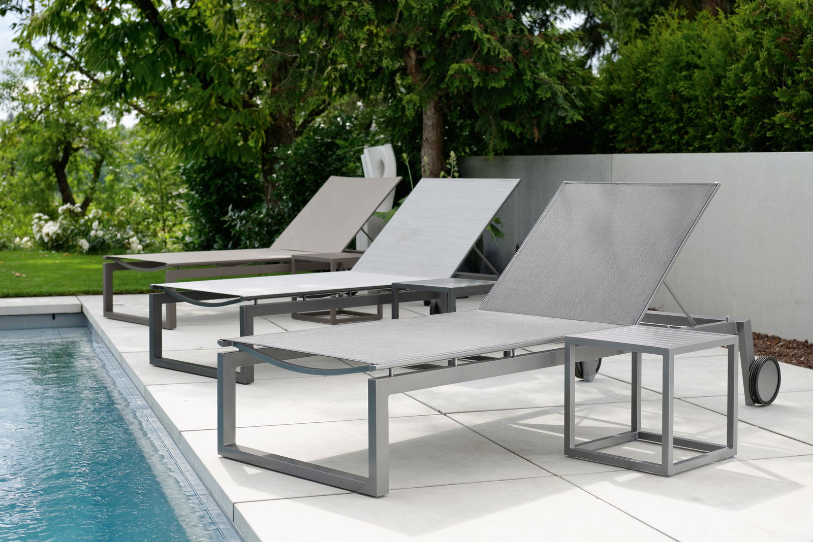 Moderne Rollenliege aus Metall in einer Gartenumgebung, seitliche Perspektive am Pool