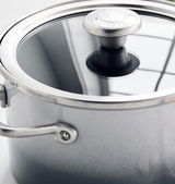 Nahaufnahme eines grauen Kochtopfs mit Glasdeckel und Edelstahlgriff, von oben betrachtet.