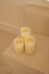 Drei cremefarbene Outdoor-Kerzen auf einer Treppe, von oben betrachtet.