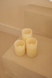 Drei cremefarbene Outdoor-Kerzen auf einer Treppe, von oben betrachtet.
