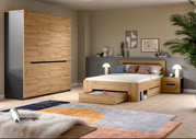 Modernes Schlafzimmer mit Holzbett inklusive Bettkasten-Schublade, passendem Nachttisch und großem Kleiderschrank in Eiche-Optik, fotografiert in schräger Frontansicht aus leicht erhöhter Perspektive.