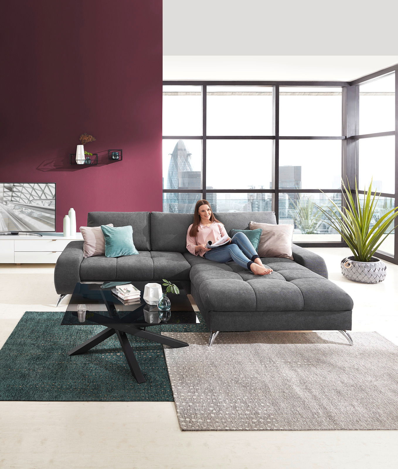 Moderner Couchtisch mit schwarzer Glasplatte und gekreuztem Metallgestell, im Vordergrund einer stilvollen Wohnzimmerumgebung mit grauem Ecksofa. Perspektive: Frontalansicht.