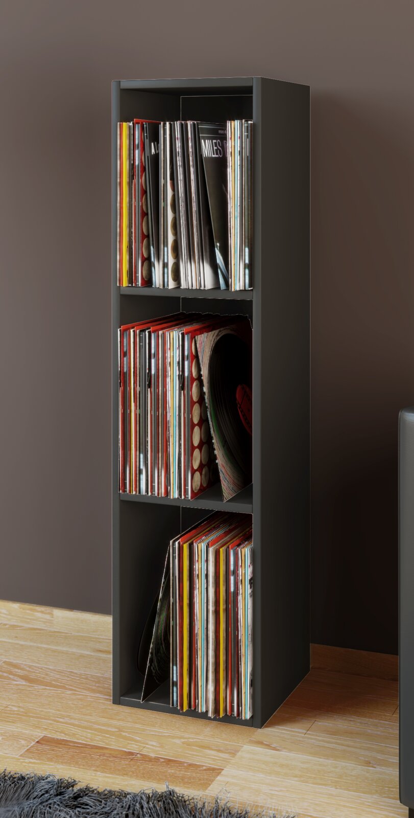 Schmales, schwarzes Regal zur Aufbewahrung von Schallplatten (Vinyl), mit drei Fächern und gefüllten LPs, freistehend im Raum; Perspektive: frontale Ansicht mit leichter Rechtsansicht.